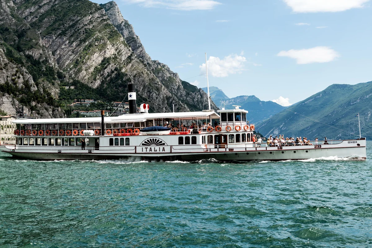 A passenger boat crossing Lake Garda with mountains behind